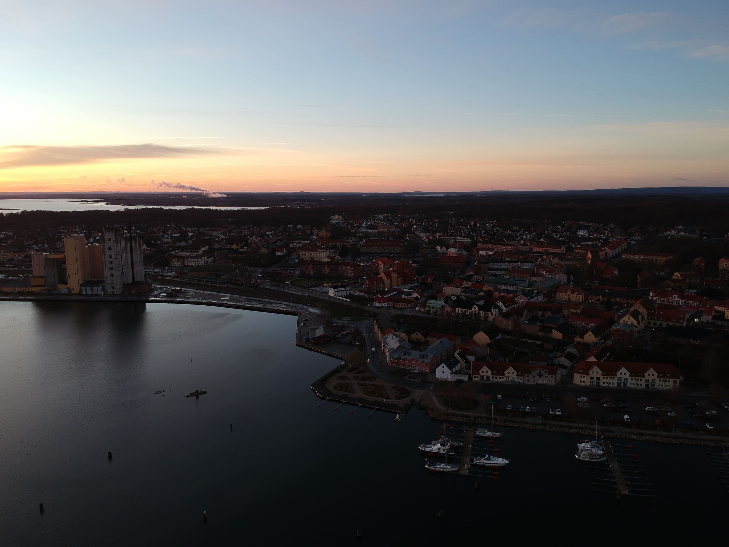 Flygfoto i skymningen över Sölvesborg med hamnen, småbåtshamnen och stadens hustak.
